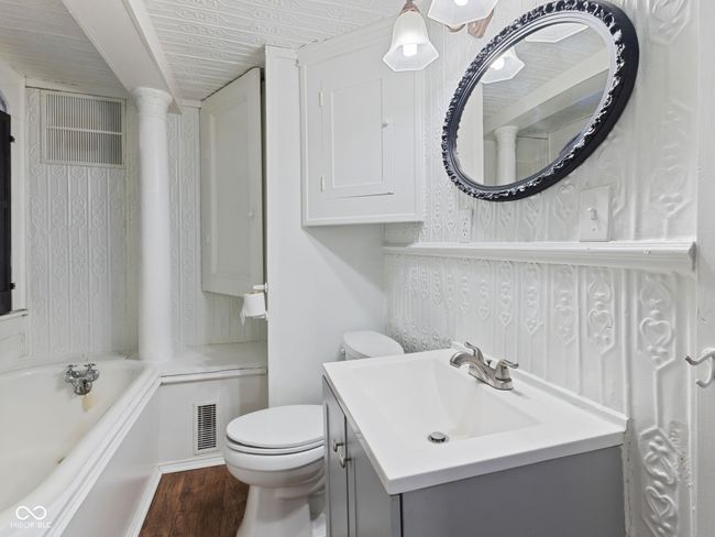 bathroom featuring toilet, vanity, a washtub, wood finished floors, and visible vents | Image 21