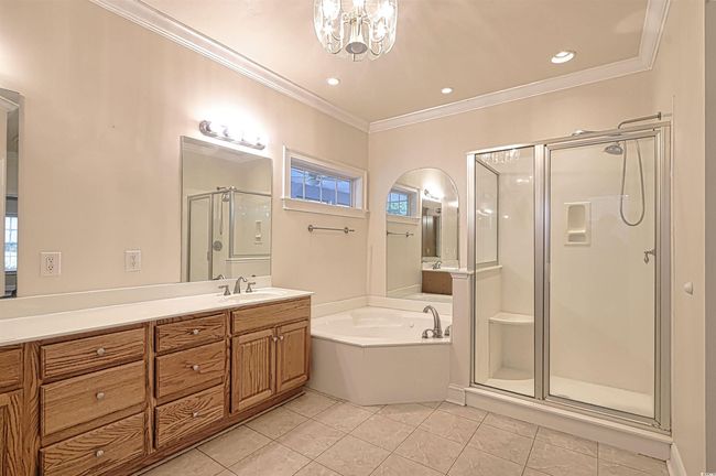 Bathroom featuring a stall shower, a garden tub, tile patterned floors, crown molding, and vanity | Image 12