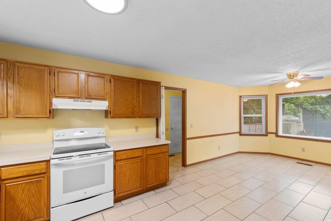 Kitchen featuring white range with electric cooktop, under cabinet range hood, light countertops, and ceiling fan | Image 7