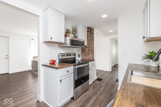 kitchen with white cabinets, visible vents, stainless steel appliances, and dark wood-type flooring | Image 14