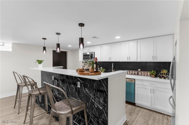 Kitchen with dishwasher, stainless steel microwave, white cabinets, backsplash, and light wood-style floors | Image 38
