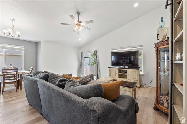 Living area with lofted ceiling, a ceiling fan, light wood-type flooring, healthy amount of natural light, and a chandelier | Image 6