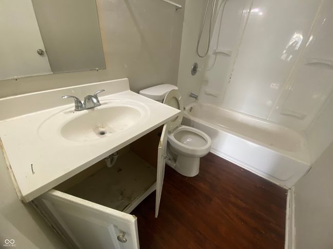 bathroom with washtub / shower combination, wood finished floors, toilet, and vanity | Image 12