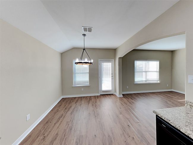 Unfurnished dining area with a chandelier, light wood-style flooring, vaulted ceiling, and arched walkways | Image 11