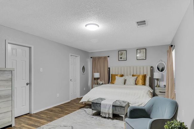 Bedroom featuring visible vents, a textured ceiling, baseboards, and wood finished floors | Image 7
