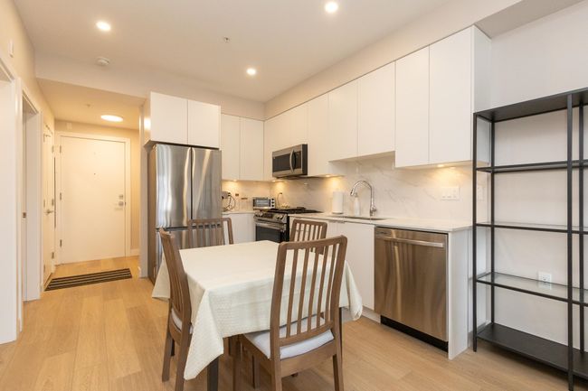 Kitchen with modern cabinets, light wood-style flooring, a sink, and appliances with stainless steel finishes | Image 12