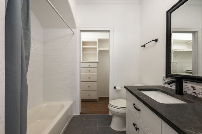 Bathroom with tile patterned floors, vanity, toilet, shower / bath combination with curtain, and decorative backsplash | Image 21