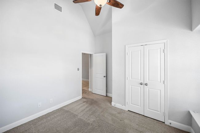 Unfurnished bedroom with baseboards, visible vents, high vaulted ceiling, a closet, and carpet flooring | Image 5