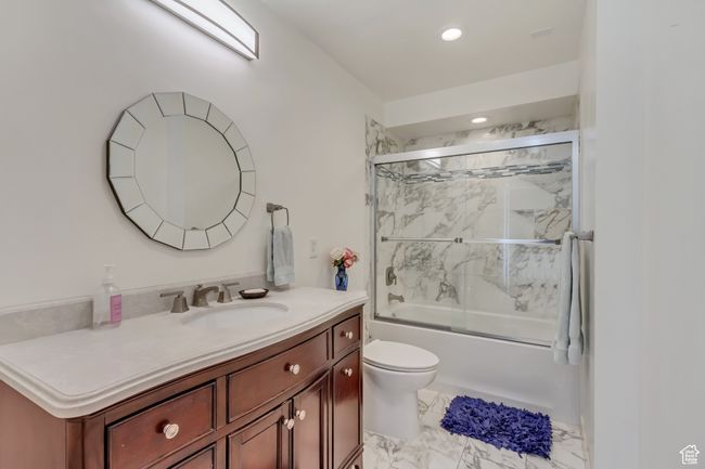 Full bathroom with recessed lighting, shower / bath combination with glass door, marble finish floor, toilet, and vanity | Image 12