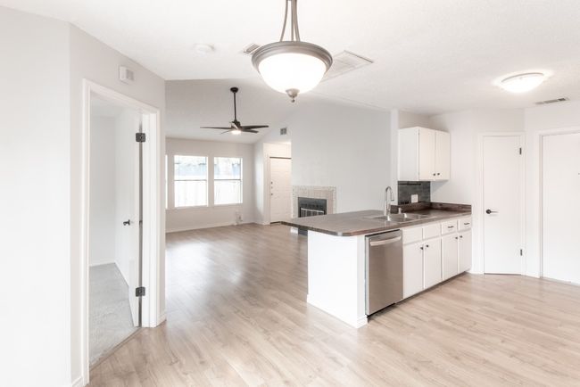 Kitchen with stainless steel dishwasher, dark countertops, light wood-type flooring, and white cabinetry | Image 10