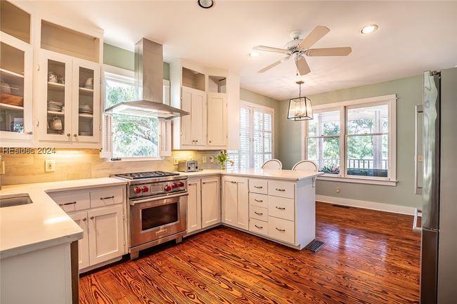 Kitchen featuring dark hardwood / wood-style flooring, range hood, pendant lighting, and stainless steel appliances | Image 18