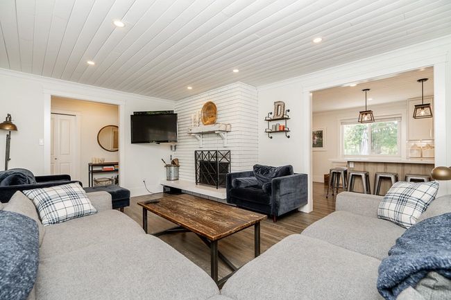 Living area featuring recessed lighting, wood finished floors, ornamental molding, and a brick fireplace | Image 12