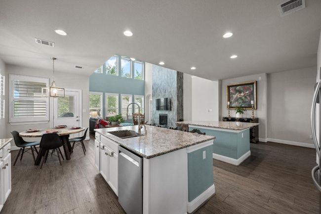 Kitchen featuring a kitchen island with sink, stainless steel dishwasher, a fireplace, dark wood finished floors, and recessed lighting | Image 12