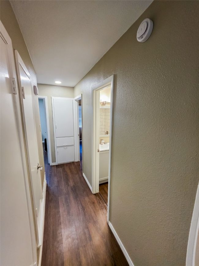 Hall with dark wood-style flooring, a textured wall, and baseboards | Image 17