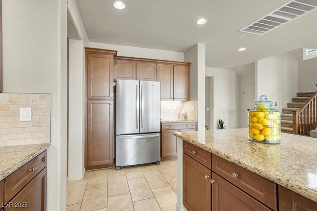 Kitchen with freestanding refrigerator, tasteful backsplash, recessed lighting, light stone countertops, and brown cabinetry | Image 19