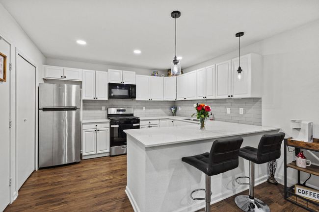 Kitchen featuring appliances with stainless steel finishes, a peninsula, white cabinets, tasteful backsplash, and recessed lighting | Image 7
