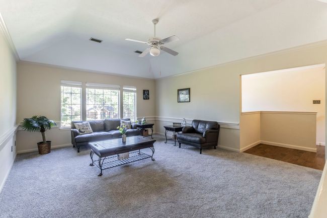 Living area featuring carpet flooring, a ceiling fan, lofted ceiling, crown molding, and baseboards | Image 17