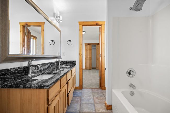 Bathroom with double vanity, shower combination, baseboards, and stone finish floors | Image 11