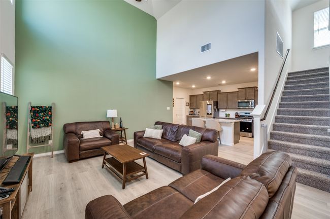 Living room with a high ceiling, visible vents, and light wood finished floors | Image 5