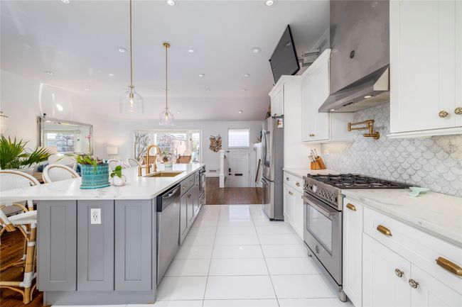 Kitchen featuring tasteful backsplash, a breakfast bar, a sink, light tile patterned flooring, and appliances with stainless steel finishes | Image 8