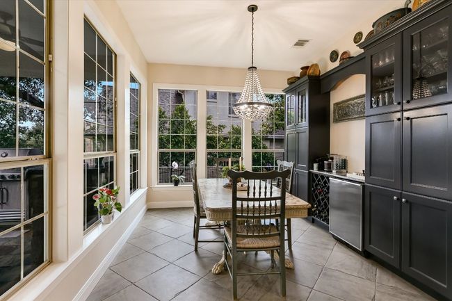 Breakfast is special in this room filled with of natural light. A beaded and brass chandelier, and built in cabinet add sophistication and warmth. | Image 11