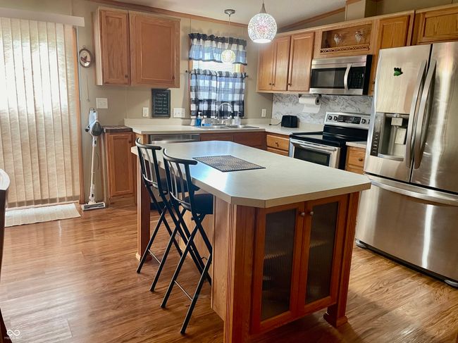 kitchen featuring stainless steel appliances, light countertops, wood finished floors, and a kitchen island | Image 6