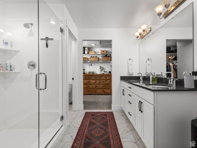 Full bath featuring marble finish flooring, double vanity, a stall shower, and a spacious closet | Image 49
