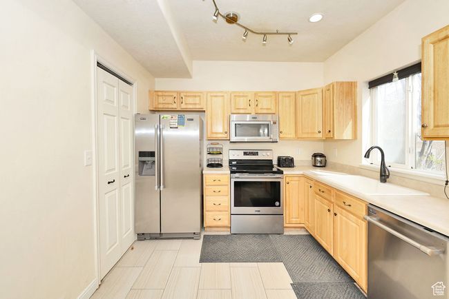 Kitchen featuring light countertops, a sink, light brown cabinetry, and appliances with stainless steel finishes | Image 4