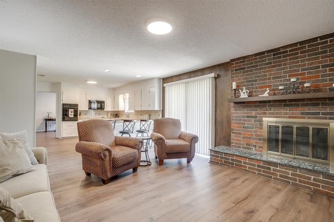 Living room with a textured ceiling, light wood-style floors, and a fireplace | Image 15