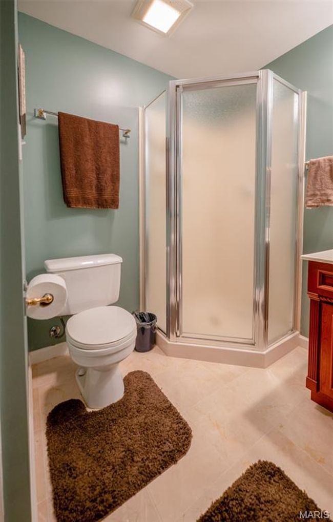 Bathroom with a stall shower, vanity, and tile patterned flooring | Image 54