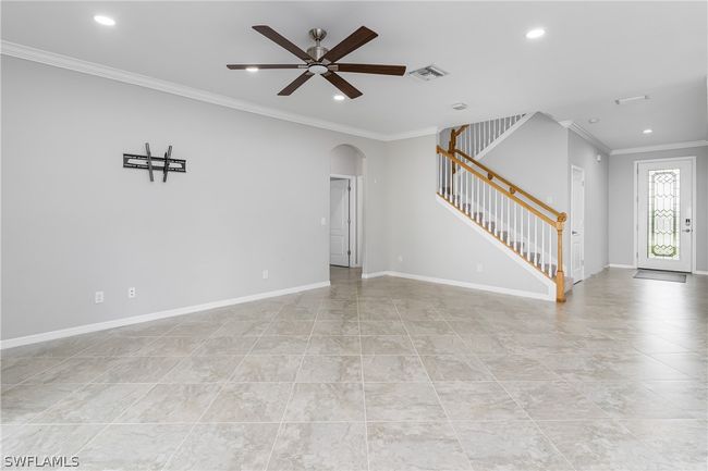 Unfurnished living room with ceiling fan, light tile flooring, and crown molding | Image 4