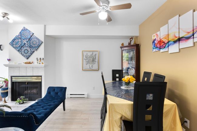 Dining space with light wood-type flooring, a baseboard heating unit, ceiling fan, and a fireplace | Image 9