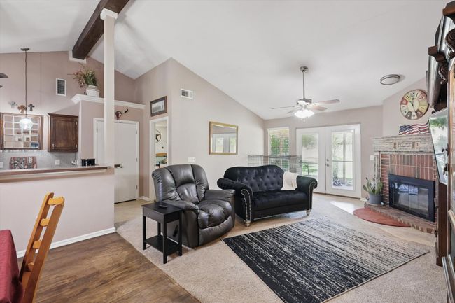 Living room with a ceiling fan, wood finished floors, visible vents, and a fireplace | Image 8