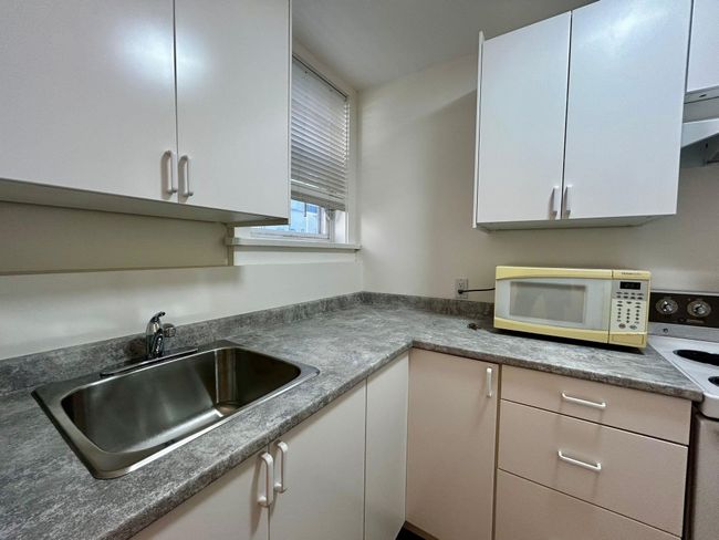 Kitchen with a sink, white cabinetry, electric range oven, and white microwave | Image 5
