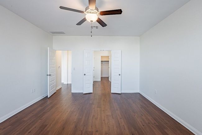 Unfurnished bedroom with dark wood finished floors, baseboards, visible vents, and a walk in closet | Image 17
