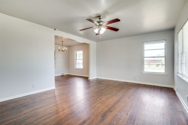 Spare room with visible vents, baseboards, dark wood-style floors, and ceiling fan with notable chandelier | Image 6