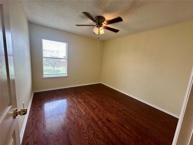 Empty room with a ceiling fan, dark wood finished floors, and a textured ceiling | Image 18