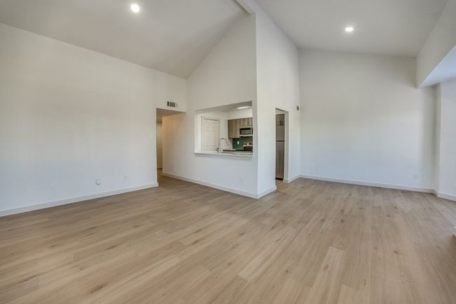 Unfurnished living room with high vaulted ceiling, sink, and light wood-type flooring | Image 5
