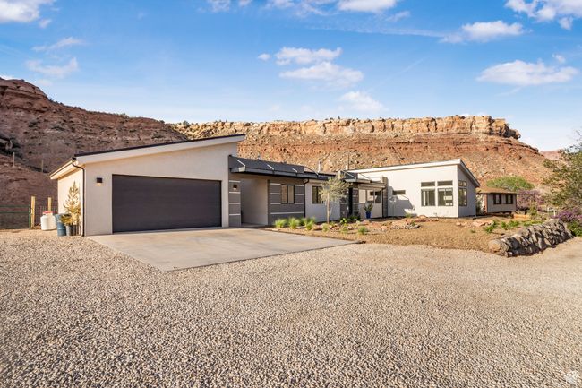 View of front of home featuring a garage, stucco siding, gravel driveway, solar panels, and a mountain view | Image 51