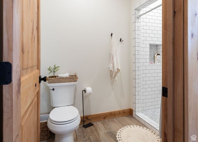 Bathroom with toilet, wood finished floors, baseboards, and a shower stall | Image 24