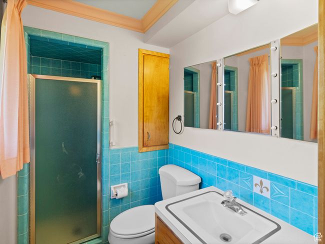 Full bathroom featuring tile walls, a shower stall, toilet, vanity, and wainscoting | Image 15