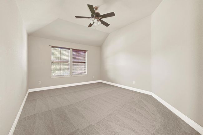Another upstairs bedroom combines carpeted comfort with natural light and architectural charm, featuring a gently sloped ceiling, large windows, and a full-entry closet outfitted with abundant built-in storage. | Image 33