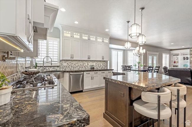 Kitchen featuring stainless steel appliances, a breakfast bar, a center island, decorative backsplash, and glass insert cabinets | Image 9
