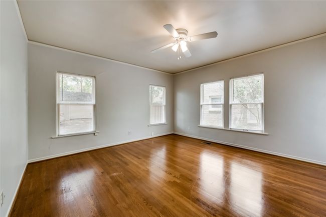 Empty room with a ceiling fan, wood finished floors, and crown molding | Image 21