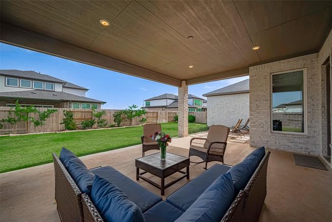 A spacious covered patio with space to relax and a view of a well-maintained backyard, perfect for outdoor relaxation and entertaining. | Image 38