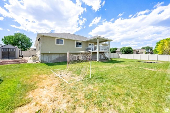 Rear view of property with stairway, a storage unit, a fenced backyard, and a deck | Image 26