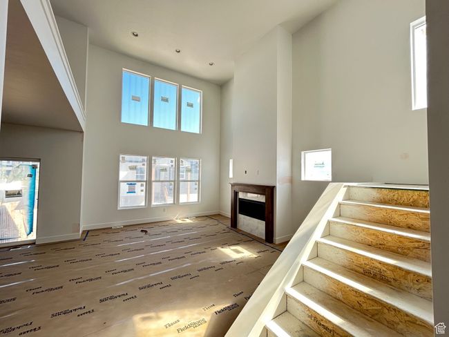 Unfurnished living room featuring a high ceiling, stairway, and a fireplace | Image 8