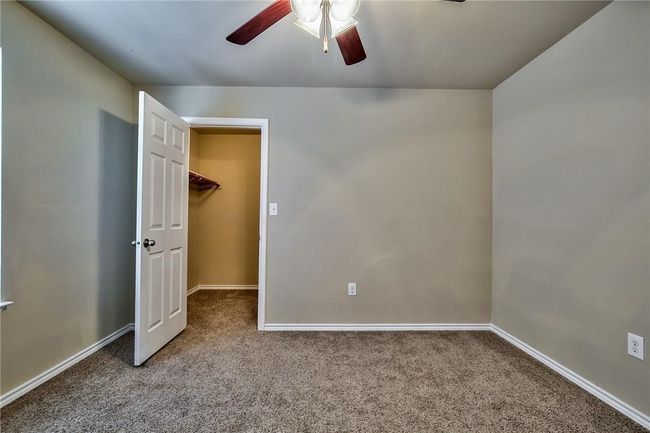 Unfurnished bedroom with carpet flooring, a walk in closet, and ceiling fan | Image 11