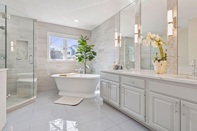 Elegantly updated primary bath features a large soaker tub, glass walk-in shower, dual vanities, beautiful fixtures and tile, plus great storage space | Image 11