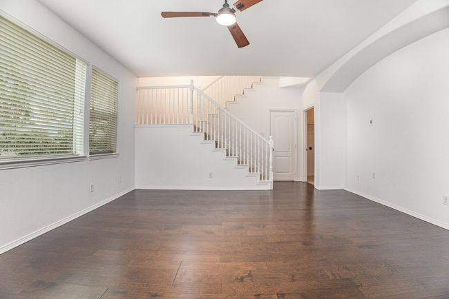 Unfurnished living room featuring baseboards, ceiling fan, stairway, and wood-type flooring | Image 5